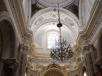 Dal soffitto dai toni celeste e oro scende un grande lampadario di cristallo